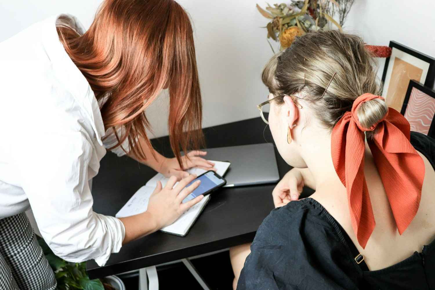 Frau in weißem Langarmshirt hält einen schwarzen Tablet-Computer.